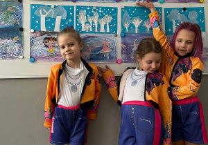 Trzy uczennice na tle prac plastycznych,