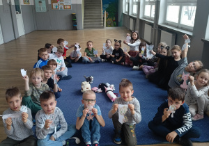 Uczniowie z klasy 1b w kocich przebraniach prezentujący wykonane prace plastyczne