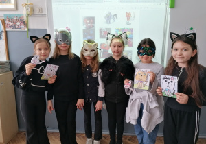 Uczniowie z klasy 2a w kocich przebraniach prezentujący wykonane prace plastyczne