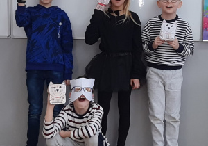 Uczniowie z klasy 3b w kocich przebraniach prezentujący wykonane prace plastyczne