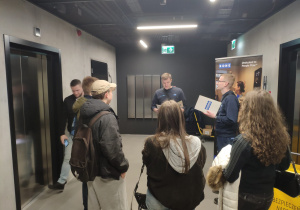 Uczniowie słuchają informacji nt. zasad funkcjonowania firmy produkującej windy osobowe i towarowe, schody ruchome, chodniki ruchome oraz drzwi automatyczne.