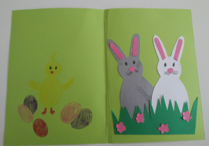 Kartka wielkanocna: po lewej stronie znajduje się narysowany kurczaczek z trzema pisankami, a po prawej dwa zające wycięte z papieru kolorowego.
