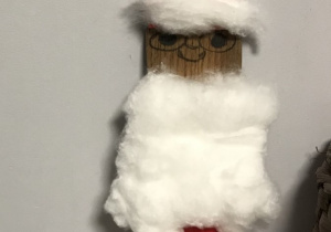 24.Kukiełka Mikołaja, wykonana z drewnianej łyżki. Mikołaj ma tradycyjny czerwono-biały strój wykonany z papieru i waty. Buzia kukiełki jest uśmiechnięta.