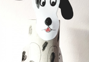 10.Pies rasy dalmatyńczyk wykonany z białej papierowej rolki, do której przymocowana jest podłużna głowa z dużymi, czarnymi uszami. Na całym ciele widoczne są czarne cętki.