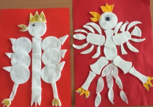Dwa białe orły wykonane z białych wacików (głowa, skrzydła, tułów, ogon, nogi) oraz żółtego papieru (korona, dziób, szpony) przyklejone na czerwonych kartonach