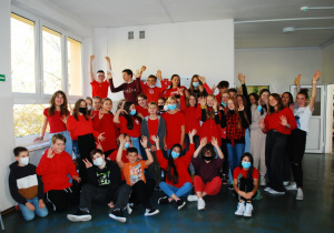 Nasi wolontariusze. Grupa młodzieży, ustawiona w trzech rzędach, ubrana w czerwone koszulki symbolizujące wolontariat w Szkolnym Kole PCK.