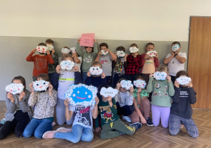 Zdjęcie przedstawia uczniów klasy z wykonanymi pracami: chmurką Tosią i swoimi chmurkami, którymi zasłonili twarze.