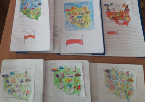 Zdjęcie przedstawia zeszyty uczniów klasy 1a, w których znajdują się pokolorowane kontury Polski oraz narysowane flagi naszego kraju.