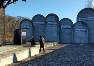 Na wystawie zewnętrznej dwóch chłopców poszukuje informacji nt. życia Żydów w getcie. W oddali widać pomnik Macew z nazwami obozów, do których wywożono ludność żydowską.