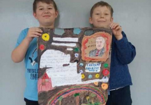 Dwóch uczniów klasy 3b trzyma wykonany przez siebie plakat przedstawiający postać Lecha Wałęsy.