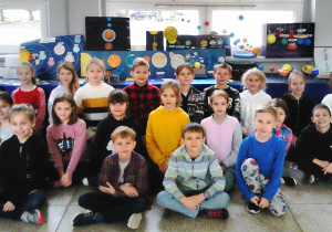 Na zdjęciu widać uczniów klasy 3a. W tle znajduje się wystawa ich prac prezentujących Układ Słoneczny.