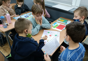Dzieci w grupach grają w przygotowane gry planszowe.