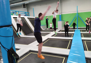 Uczniowie skaczą na trampolinach podczas rozgrzewki.