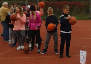 Uczniowie przygotowujący się do biegu z kozłowaniem piłki.