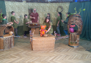 Zdjęcie przedstawia uczniów podczas warsztatów teatralnych wraz z osobą prowadzącą zajęcia; uczniowie realizują zlecone zadanie.