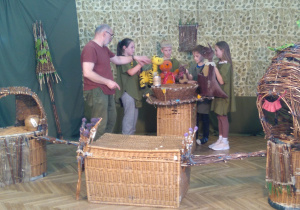 Zdjęcie przedstawia uczniów podczas warsztatów teatralnych wraz z osobą prowadzącą zajęcia; uczniowie realizują zlecone zadanie.