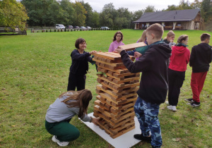 Grupa uczniów układa wieżę z klocków jenga