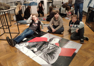 Grupa chłopców przy puzzlach z sylwetką Stanisława Szeptyckiego.