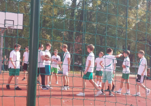 Uczniowie rozgrywający mecz koszykówki na boisku szkolnym.