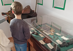 Zdjęcie przedstawia ucznia klasy 1b oglądającego eksponaty znajdujące się w Muzeum Armii Krajowej Okręgu Wileńskiego