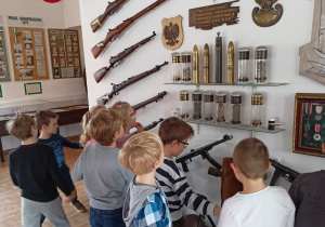Zdjęcie przedstawia uczniów klasy 1b oglądających eksponaty znajdujące się w Muzeum Armii Krajowej Okręgu Wileńskiego