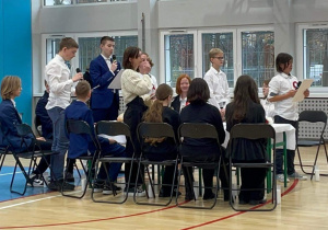 Zdjęcie przedstawia uczniów klas ósmych, czytających wiersze.