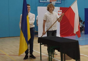 Zdjęcie przedstawia uczniów klas ósmych trzymających flagi obu narodów.