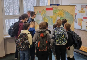 Uczniowie stojący przy mapie i zapoznający się z krajami grającymi w naszej grupi