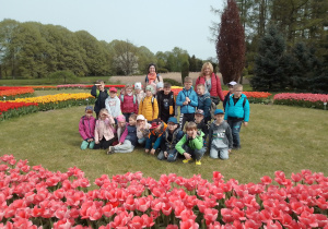Zdjęcie przedstawia uczniów klasy I z nauczycielkami w otoczeniu kwitnących tulipanów.