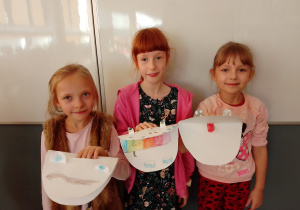 Dziewczynki prezentują wykonane prace - paszcze "stworów" zrobione z papieru