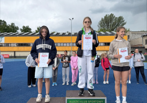 Zdjęcie z indywidualnej dekoracji 3 zawodniczek na podium, trzymających w rękach dyplomy.